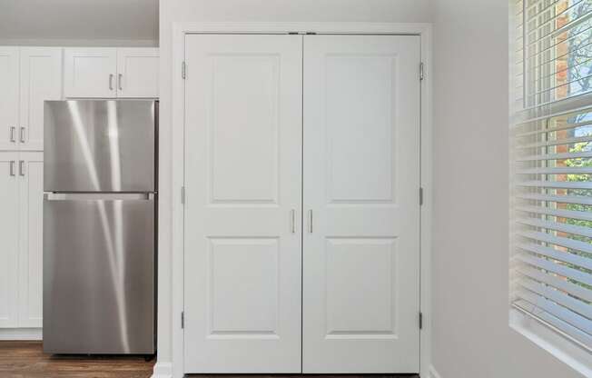 a kitchen with white doors and a stainless steel refrigerator