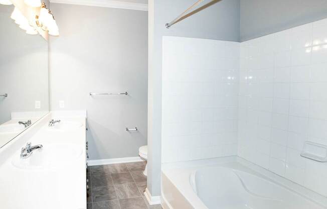 A white bathroom with a tub, sink, and toilet.