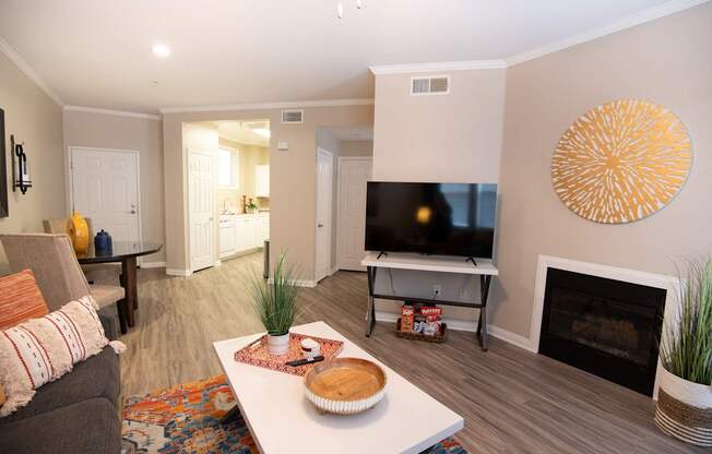 A living room with a grey couch, a white coffee table, a television, and a fireplace.