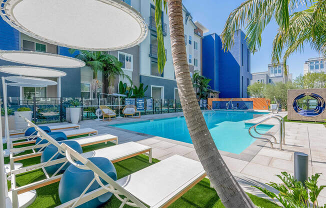 A pool area with lounge chairs and umbrellas.