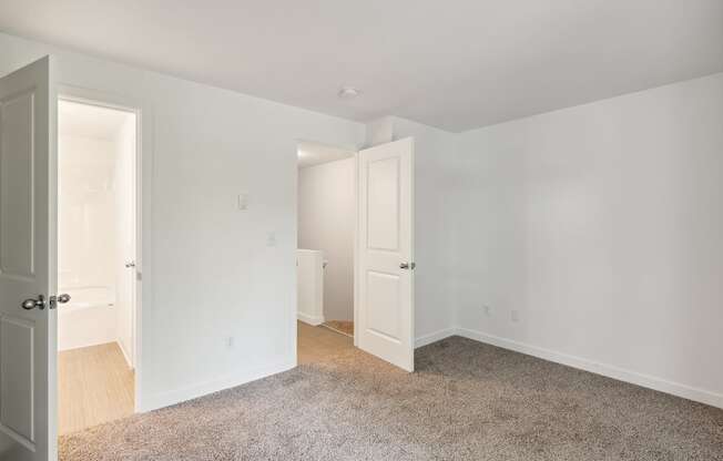 a bedroom with white walls and white doors and a carpeted floor