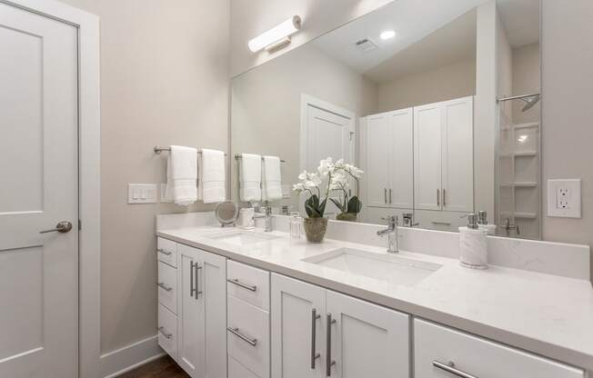a white bathroom with two sinks and a mirror