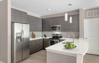 A modern kitchen with a stainless steel refrigerator and a white countertop.