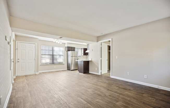 the living room and kitchen of an empty apartment with wood flooring