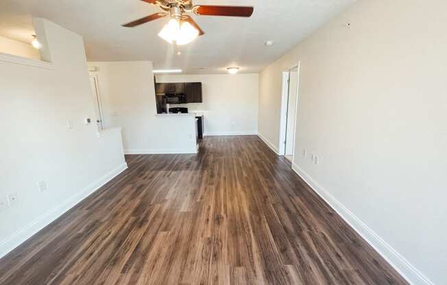 an empty living room with a ceiling fan and wood flooring