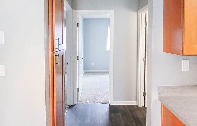 A hallway with wood floors and white walls.