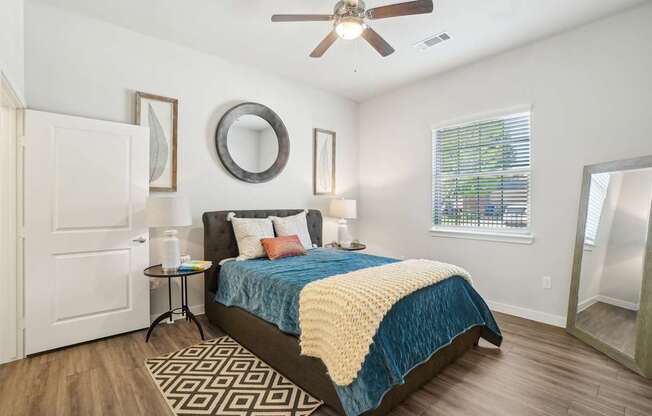 A bedroom with a bed, a ceiling fan, and a mirror on the wall.