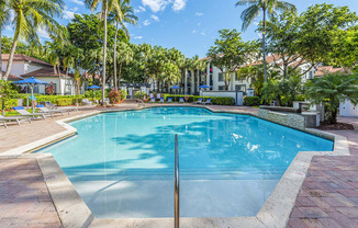 A large swimming pool surrounded by palm trees and lounge chairs.