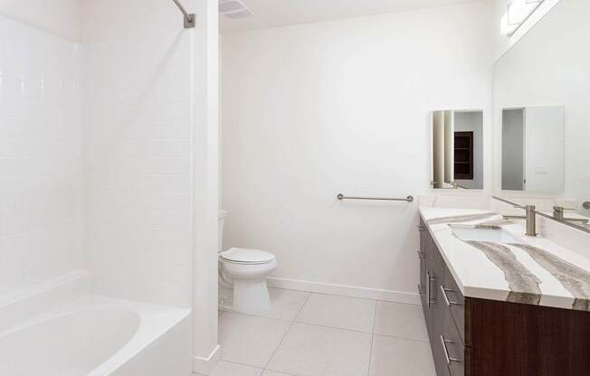 A white bathroom with a toilet, sink, and bathtub. at Elements Apartments*, Irvine, 92612