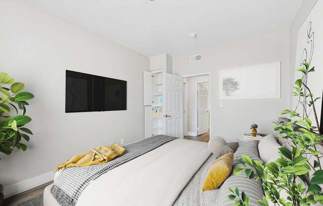 A bedroom with a bed, a TV, and a plant.