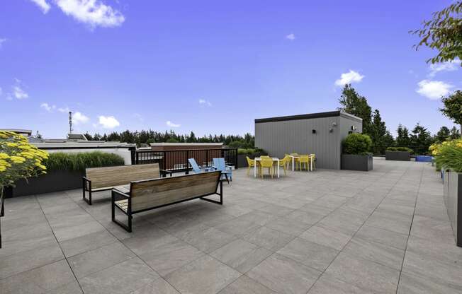 Resident Rooftop Lounge with yellow flowers and benches, chairs, and firepit to lounge by while enjoying rooftop views at Arabella Apartment Homes, Shoreline, WA