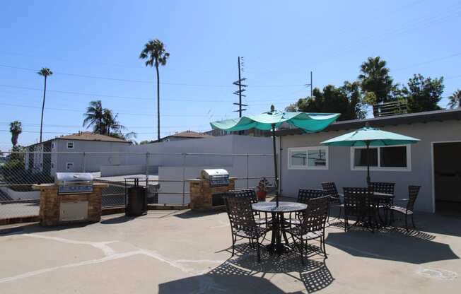 a patio with a grill and tables and umbrellas