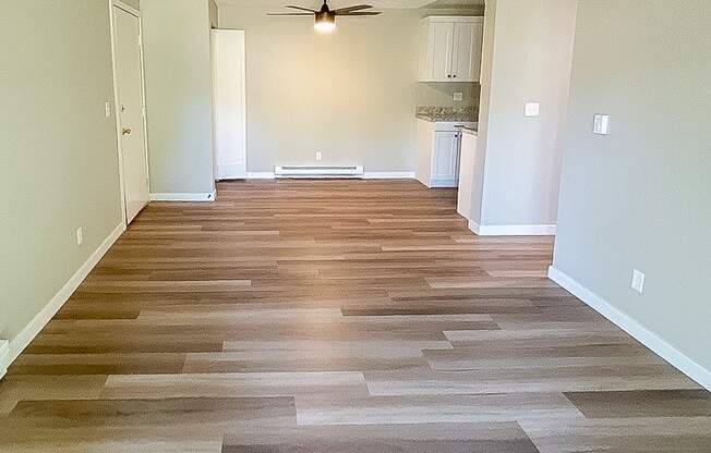 A long hallway with wood flooring and a ceiling fan.