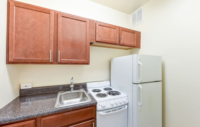 kitchen with wood cabinetry, electric range and refrigerator at eddystone apartments in washington dc