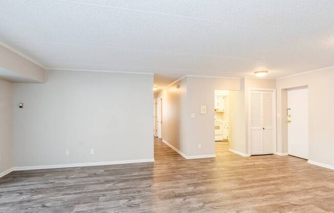 A spacious room with wooden flooring and white walls.