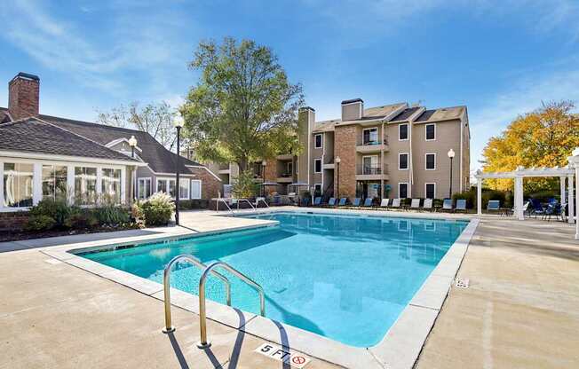 A swimming pool surrounded by a concrete floor and a metal ladder.