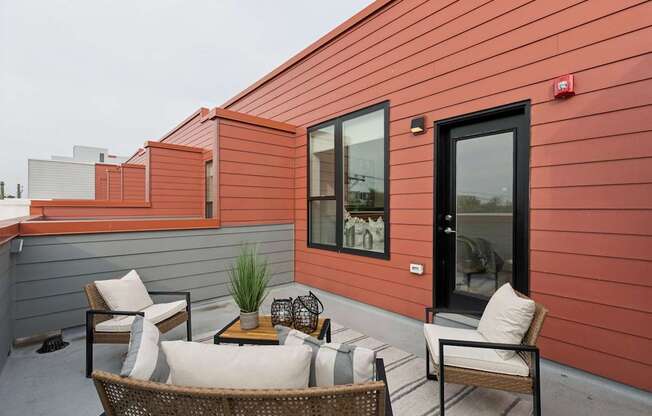 A patio with a table and chairs is on a red building.