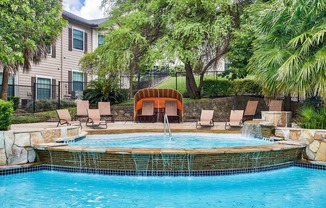 Mission oaks pool with waterfall surrounded by trees and beach chairs and club house