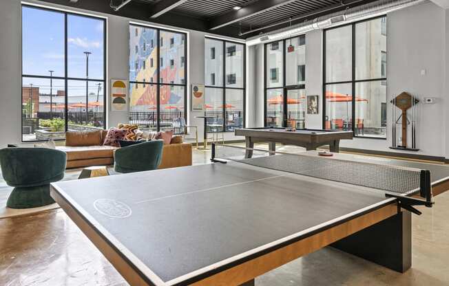 a ping pong table sits in the middle of a room with large windows  at The Icon, Richmond, VA, 23230