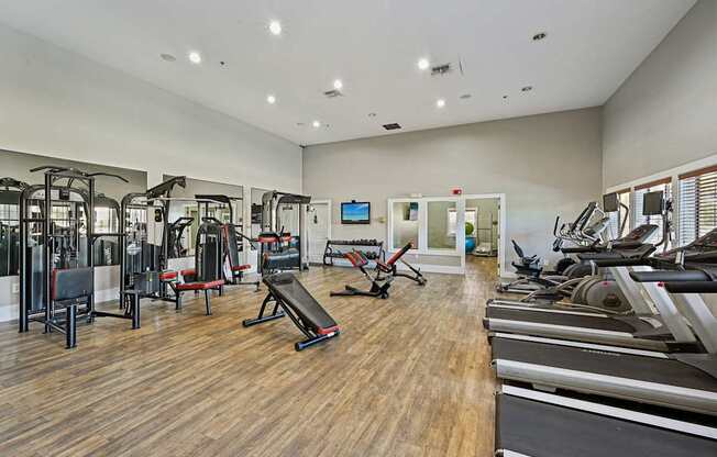 a gym with treadmills and other exercise equipment on a wooden floor