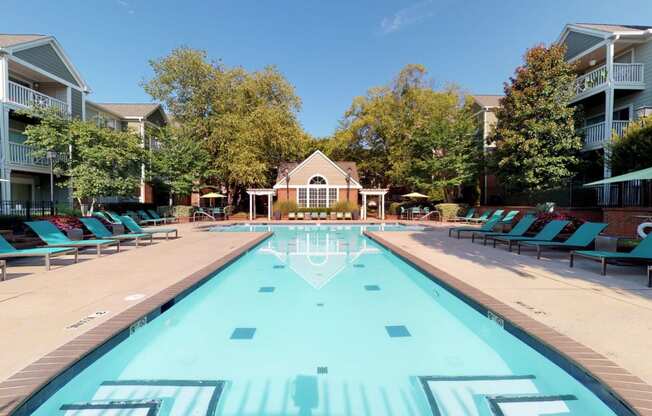 a swimming pool with blue chaise lounge chairs and a house in the background  at Autumn Park Apartments, Charlotte, North Carolina