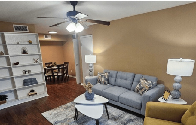 A living room with a grey couch, a white coffee table, and a yellow chair.