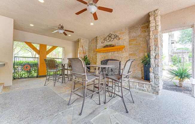 A patio with a table and chairs and a ceiling fan.