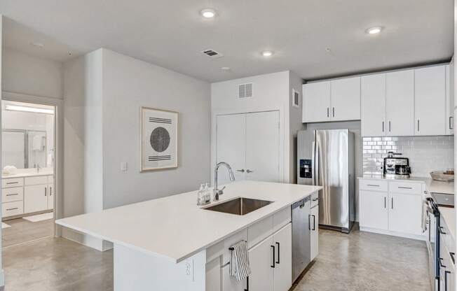 an open kitchen with white cabinets and a white island with a sink