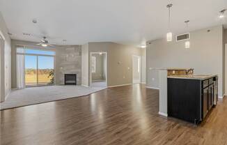 A spacious living room with a fireplace and a kitchen area with a countertop and cabinets.