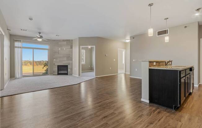 A spacious living room with a fireplace and a kitchen area with a countertop and cabinets.