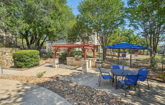 A backyard with a table and chairs and a red archway.