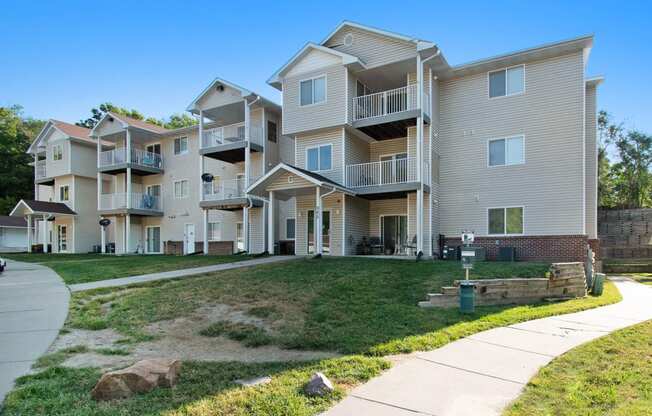 Omaha, NE Deerfield Apartments. An exterior view of an apartment complex with a sidewalk in front of it