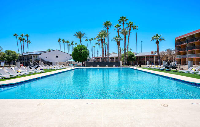a large pool with palm trees in front of a hotel at Presidio Palms Apartments, Tucson