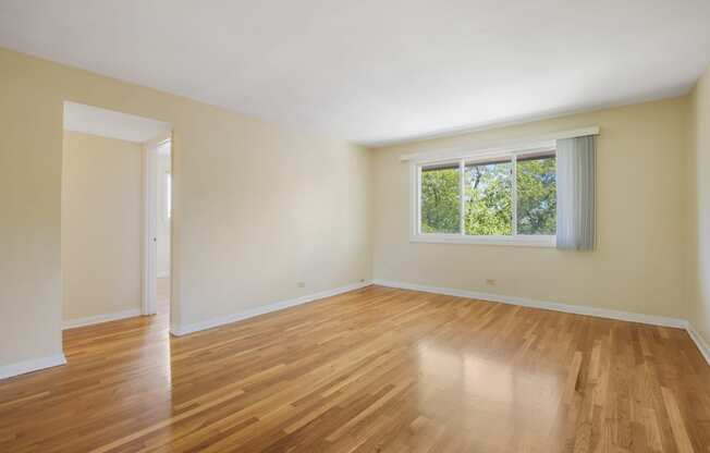 an empty living room with wood floors and a window