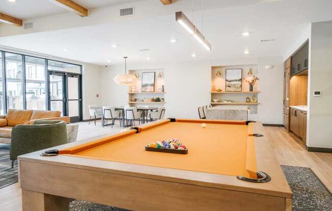 A clubroom with a orange felt pool table.
