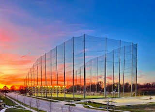 A long, tall, transparent fence stretches across a grassy field.