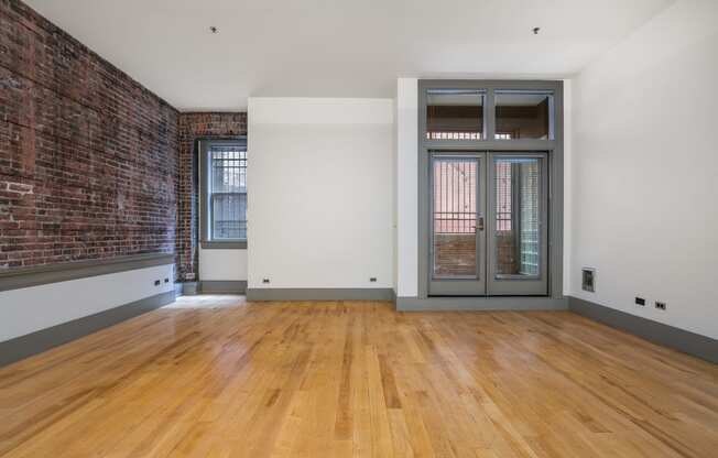 an empty living room with a brick wall and a glass door