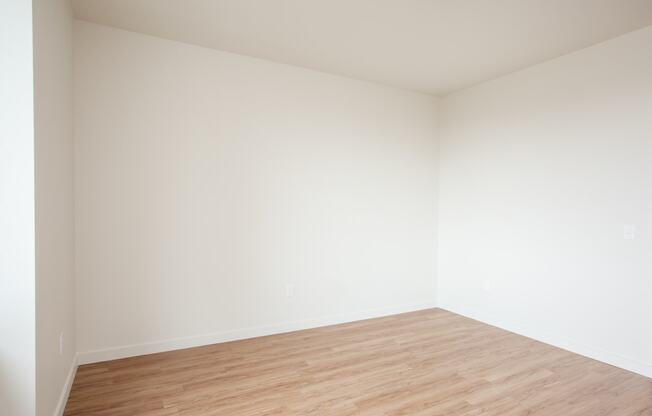 an empty room with wood floors and white walls