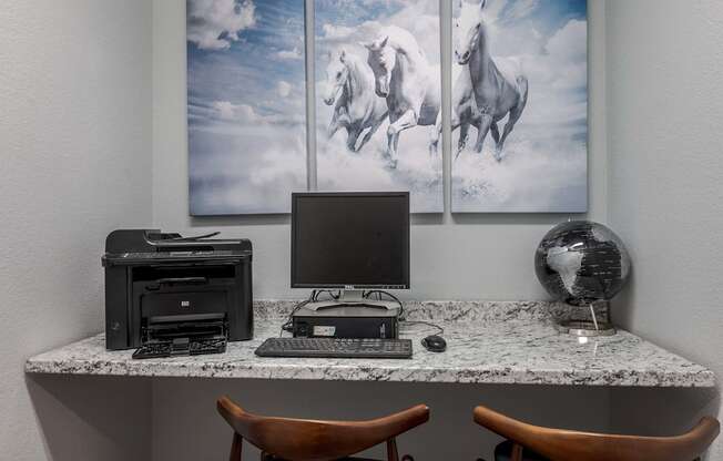 a desk with a computer and three pictures of horses on the wall
