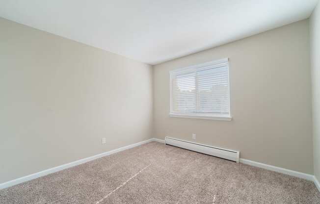 Bedroom with window, carpet, and baseboard heater