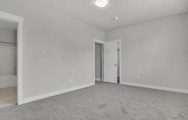 A room with a carpeted floor and two doors.