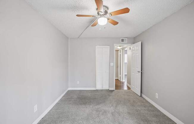 A room with a ceiling fan and carpeted floor.