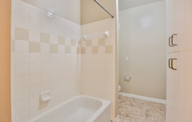 a bathroom with white tile and a white bathtub