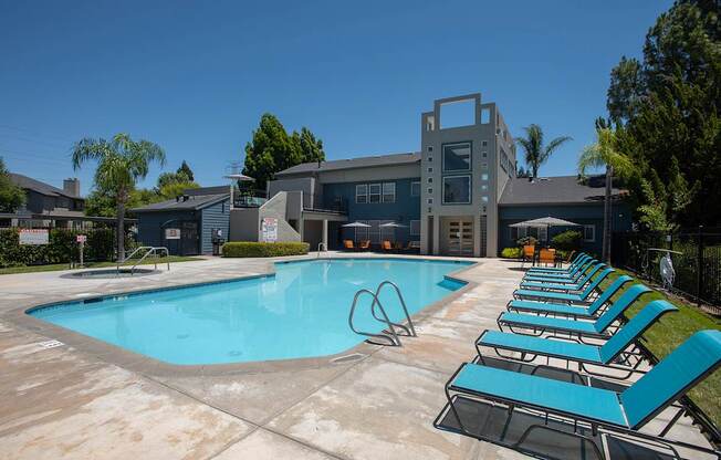 A swimming pool with blue water and lounge chairs at Autumn Oaks Apartments, Roseville, CA, 95678