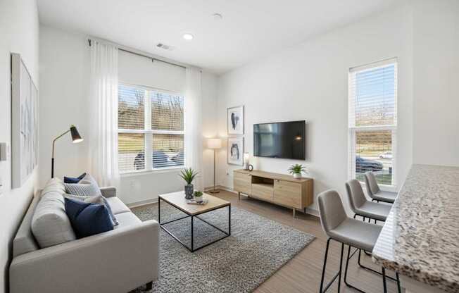 A modern living room with a grey sofa, a black coffee table, a wooden cabinet, and a television.
