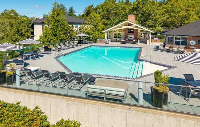 A large swimming pool surrounded by lounge chairs and umbrellas.