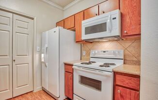 Kitchen with a sink, pantry door, white fridge, white stove top/oven, white microwave and wood cabinets with a marble countertop