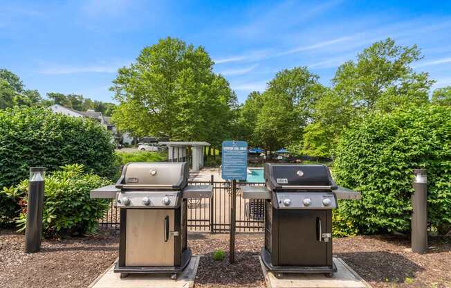 Two grills are in a fenced area with a sign in the background.