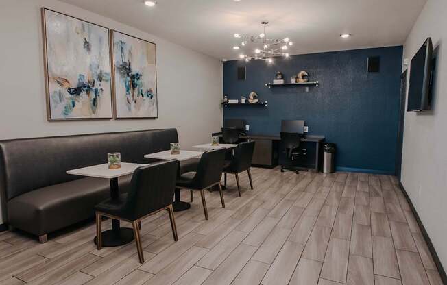 Cafe style seating and two computers against a dark blue wall and chandelier.