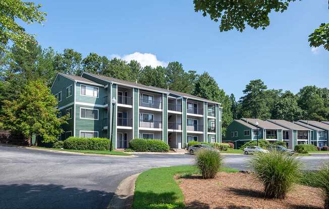 Apartment complex with green trees and a clear blue sky.